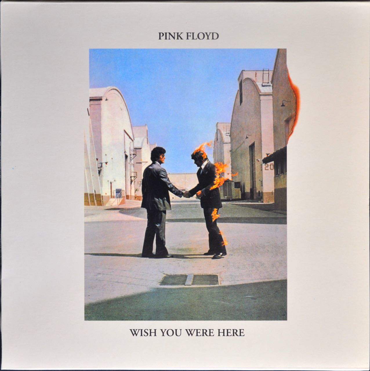 Wish You Were Here, album cover. Two men, in an alley, shaking hands and one is on fire.